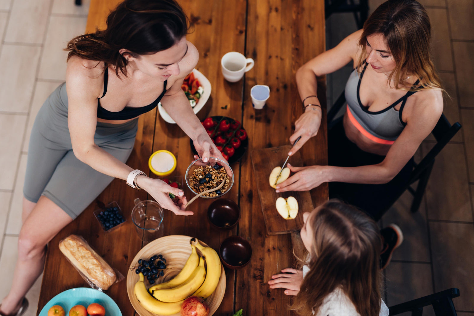 Fitness women in gym gear eating healthy snacks of fruit and nuts