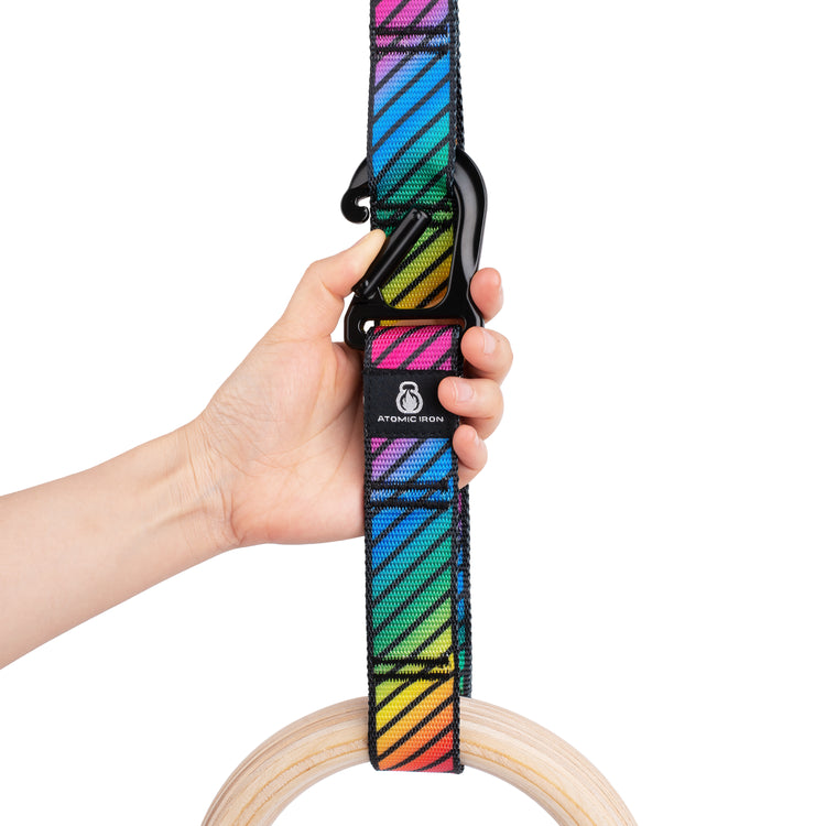 Hand clipping carabiner onto rainbow gymnastic rings strap - Atomic Iron