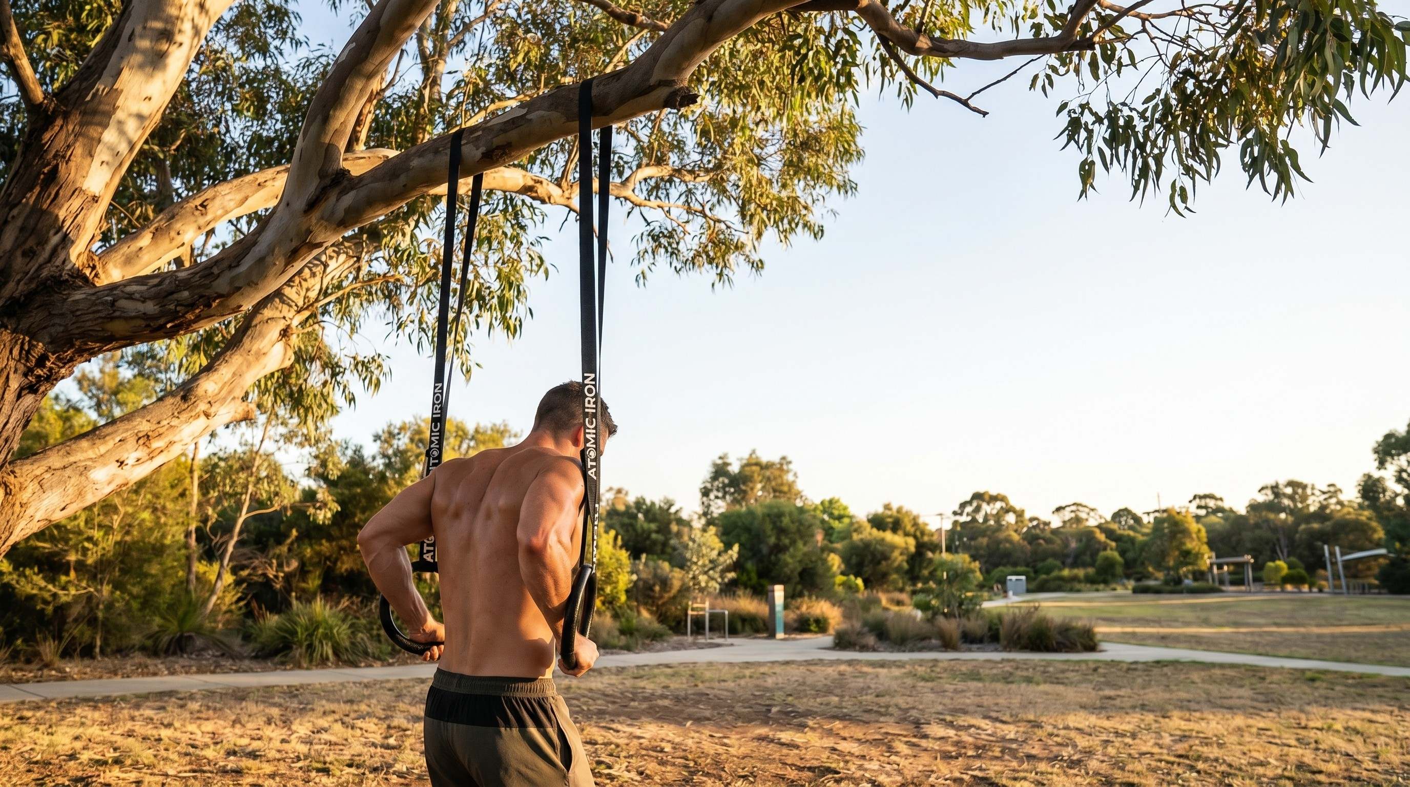 Man training on Atomic Iron premium outdoor gymnastic rings in an Australian park